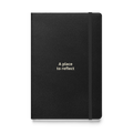 Supplier-generated mockup of the saved A Place to Reflect design: black hardcover journal with two lines of warm cream lettering, an elastic closure, and no additional gifts.